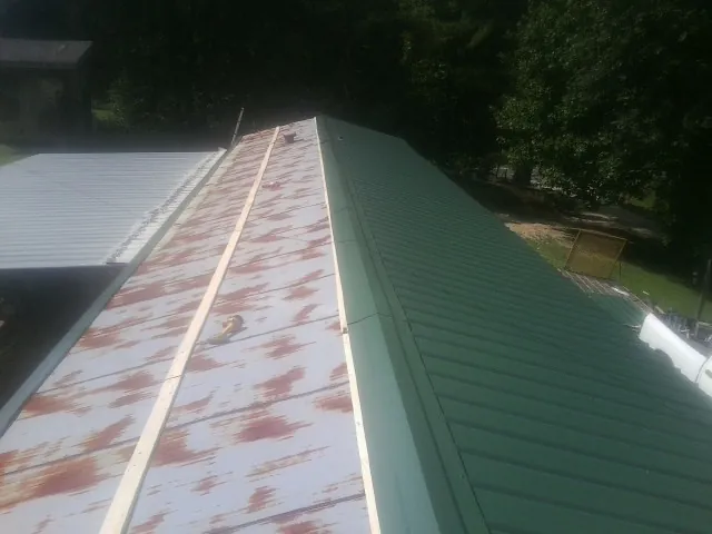 Old rusted panels beside newly installed green metal roofing — Wind Damage Roof Repair by Roofing Brothers in Parkersburg