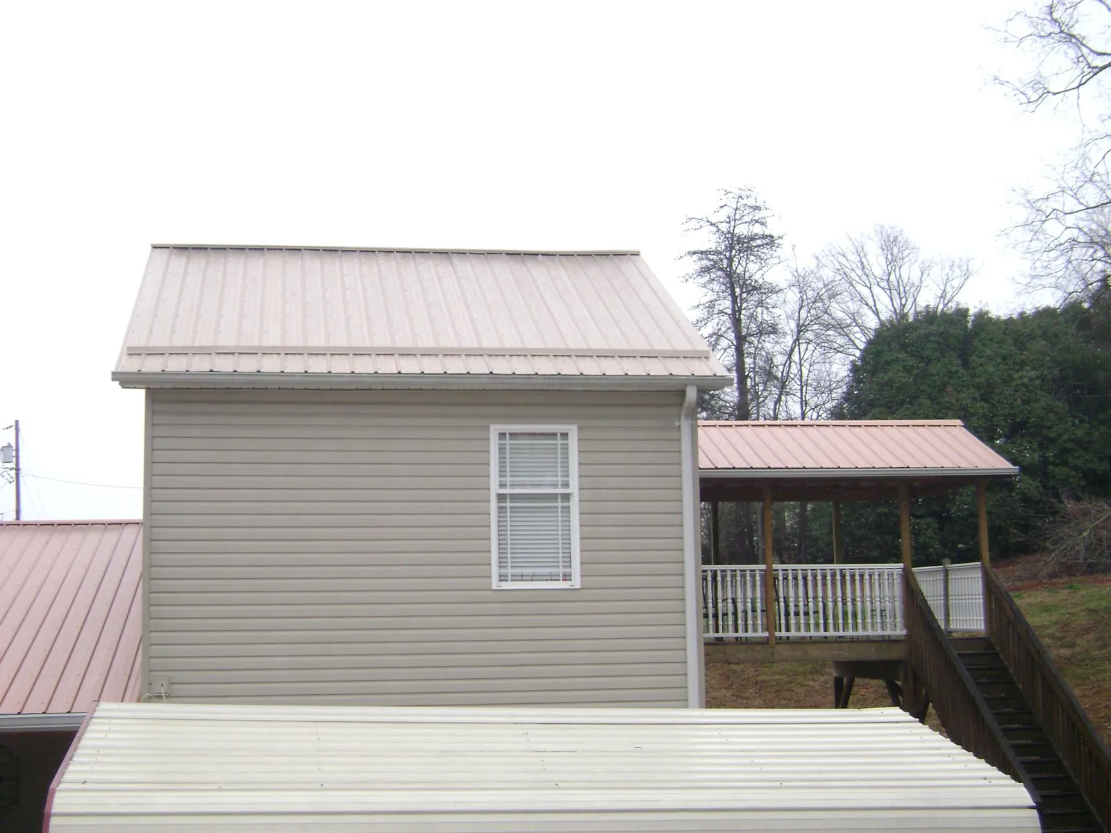 Tan metal roofs on a two story addition and attached porch, from a Roof Replacement job in Parkersburg